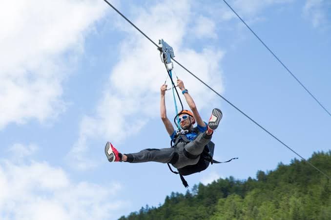 Zip-line rider gliding over a forested valley