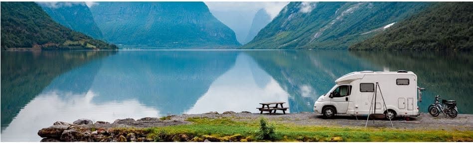 Motorhome parked beside a calm fjord among mountains