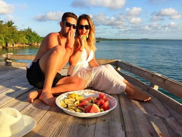 Couple enjoying fruit on a jetty at sunset