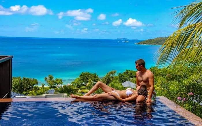 Couple relaxing in an infinity pool over the sea