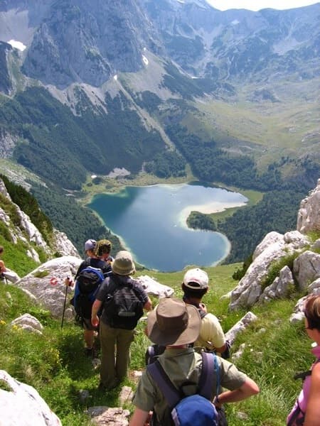 Hikers above the heart-shaped Trnovačko lake in the Balkan mountains