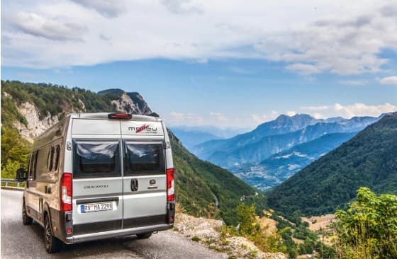 Camper van on a mountain road overlooking a Balkan valley