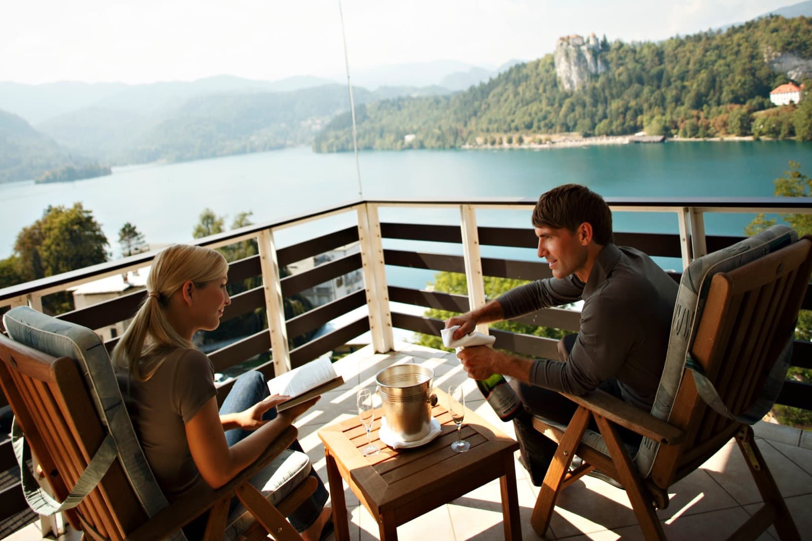 Couple on a balcony with sparkling wine overlooking Lake Bled